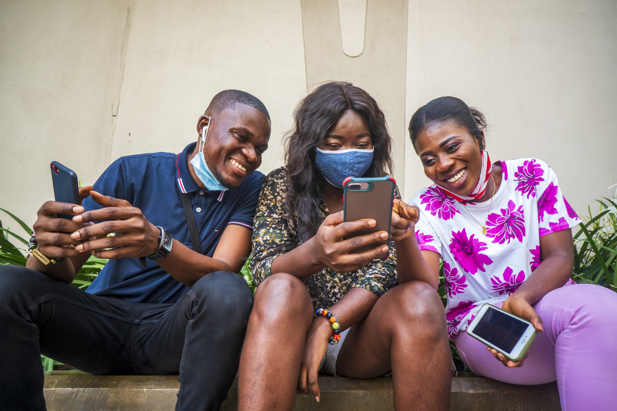 group young friends protective face masks using their phones outdoors scaled